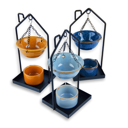 Set of ceramic bowls in orange and blue on black metal stands with chains.