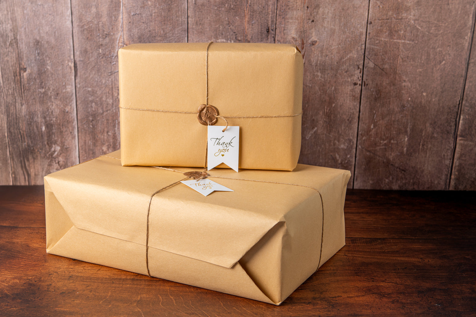 Two packages wrapped in brown paper with tags on a wooden surface and background.