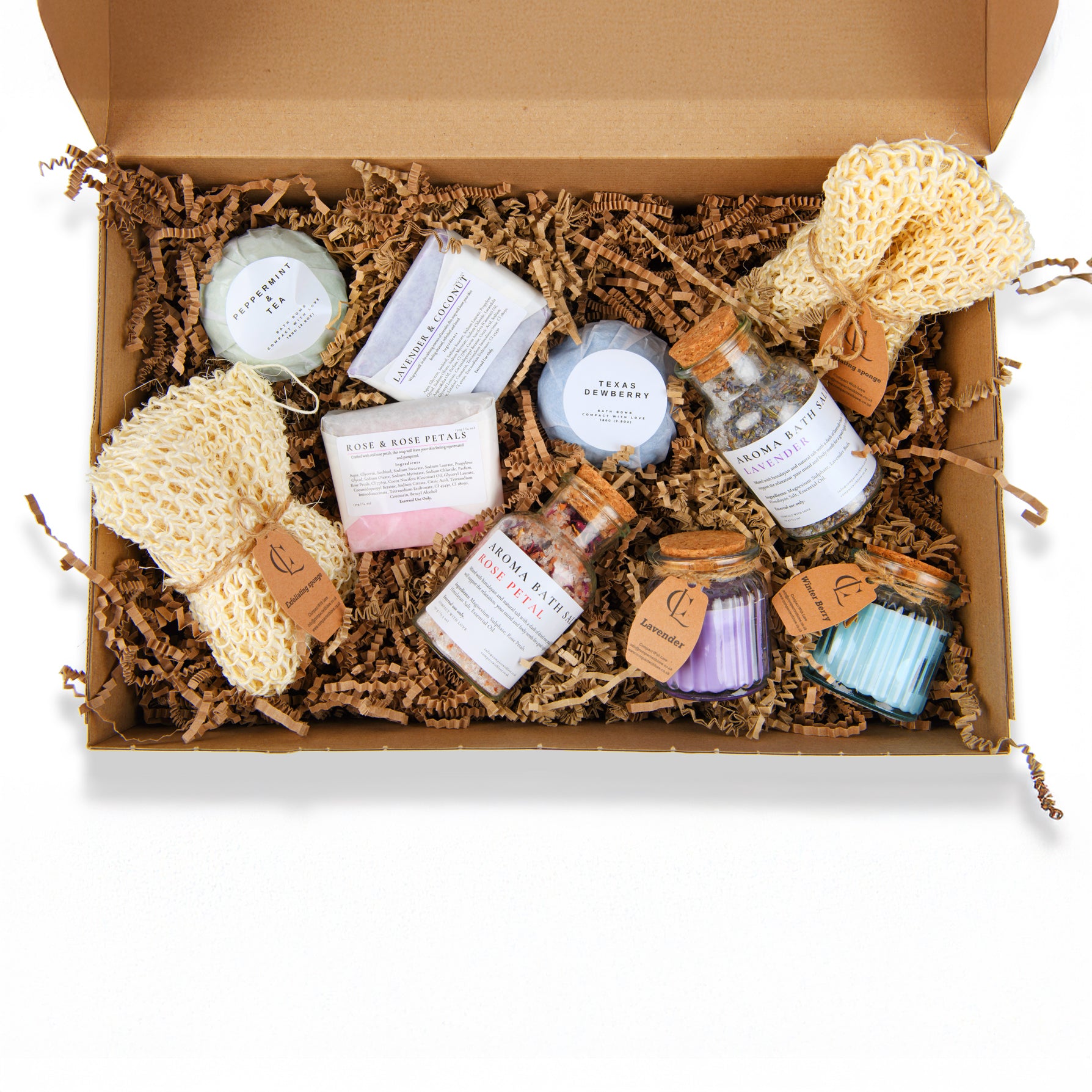 Box of bath products including soaps, candles, and loofahs on a white background