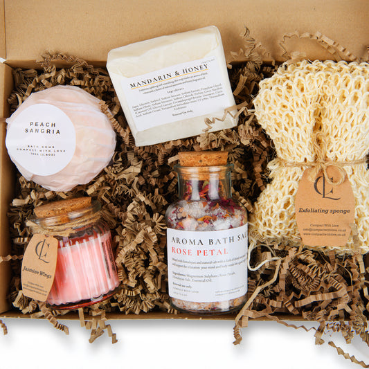 Bath and body products including a bath bomb, soap, candle, and bath salts in a box.