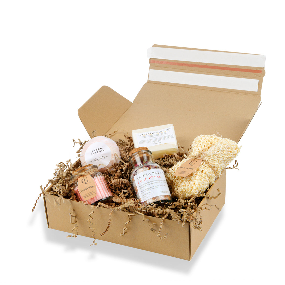 Open cardboard box with bath products including a loofah, soap, and bath bombs on a white background