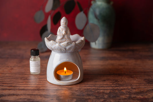 Aroma lamp with a lit candle and a small bottle on a wooden surface.