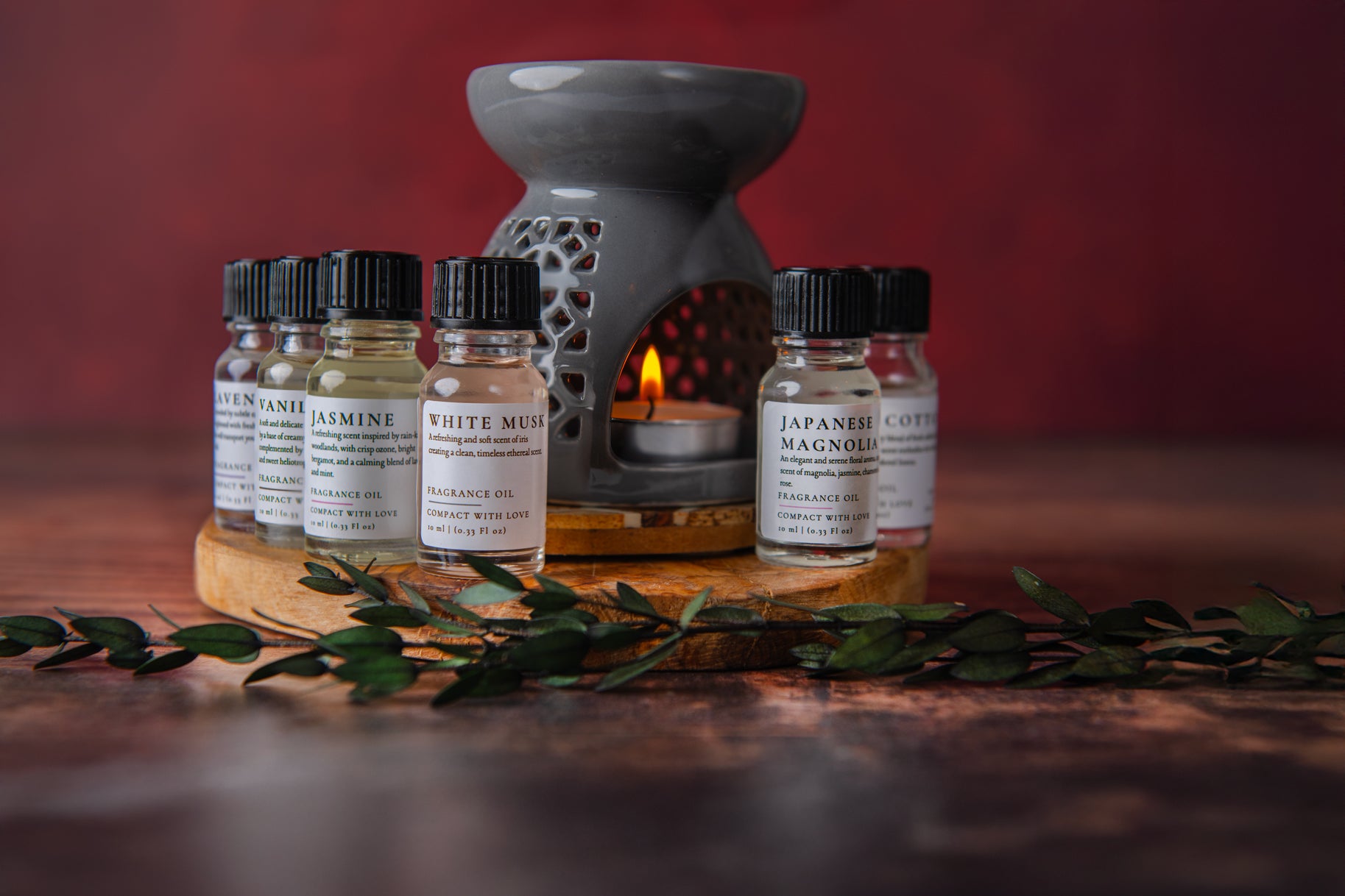 Set of essential oil bottles with a diffuser on a wooden surface against a red background