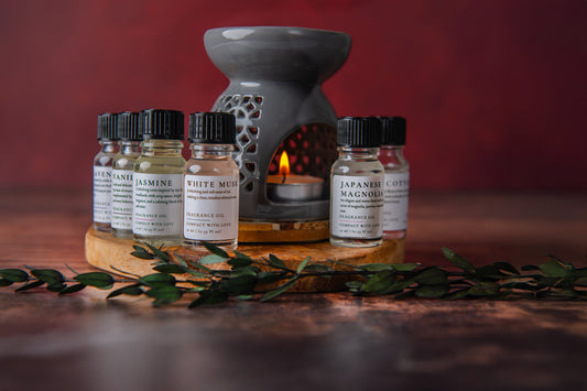 Set of essential oil bottles with a diffuser on a wooden surface against a red background