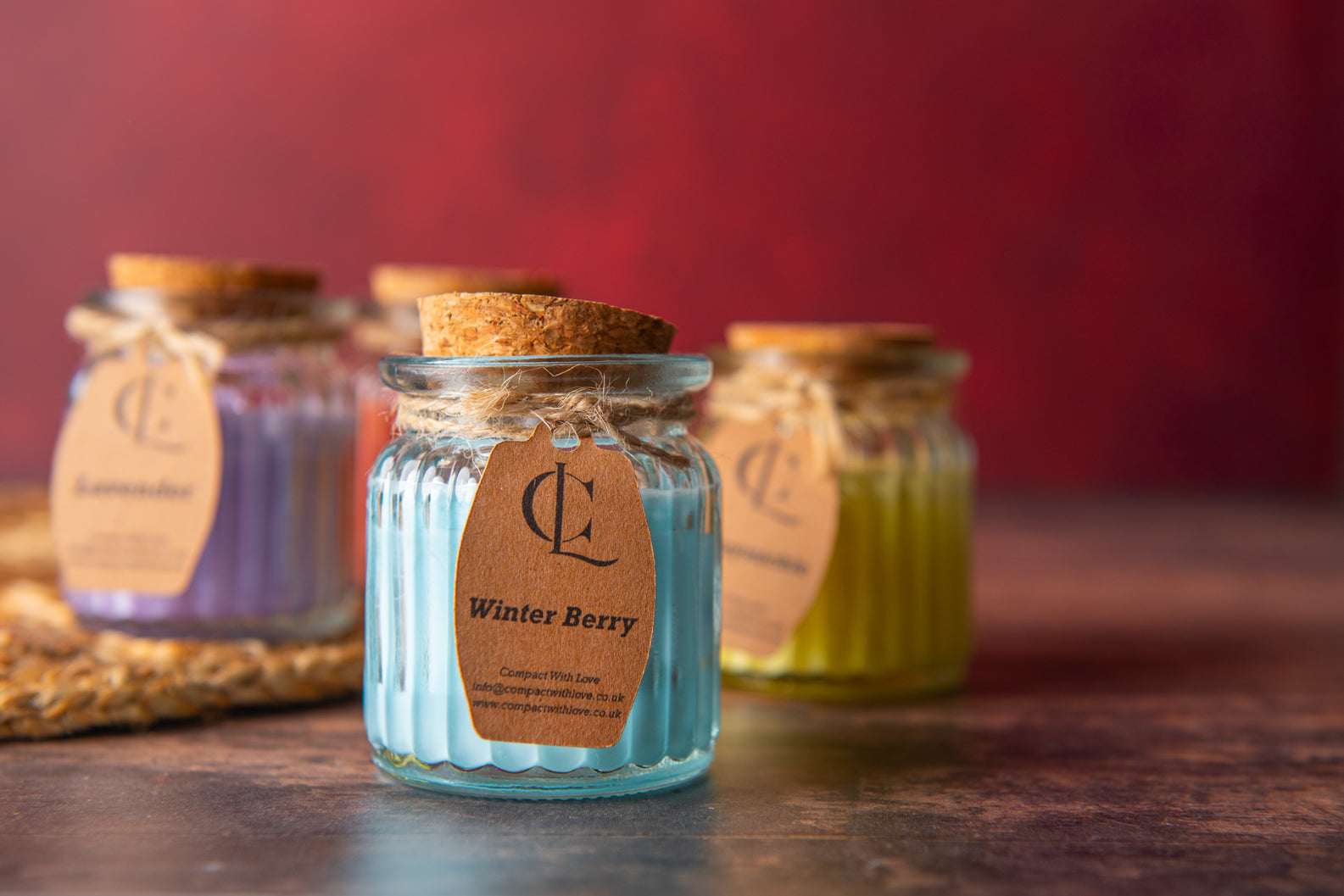 Small glass jars with cork lids and 'Winter Berry' label on a wooden surface.