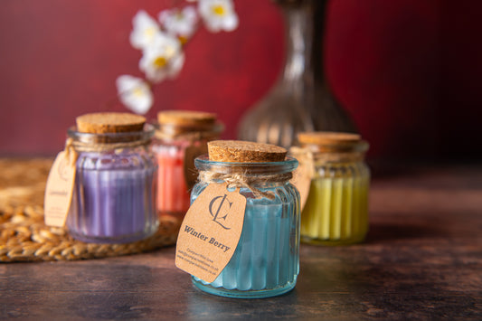 Jars of colorful candles with visible labels on a wooden surface.